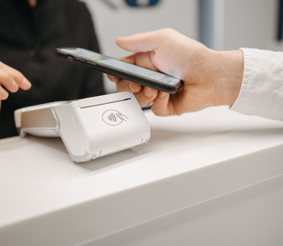A customer tapping a phone on a contactless payment terminal